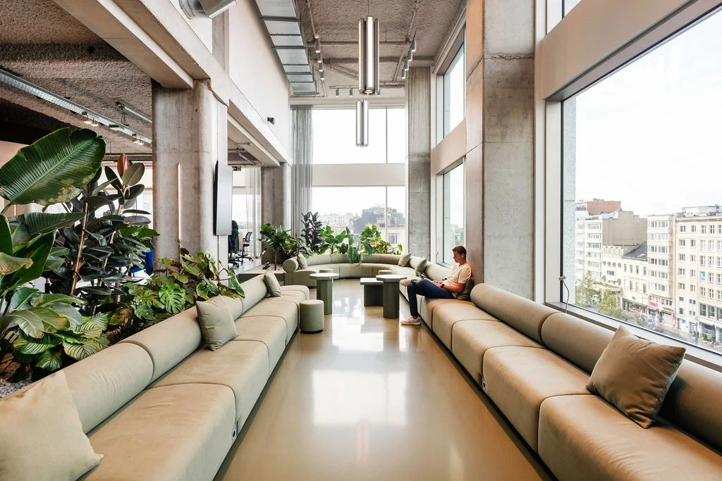 Het lichte interieur van Silversquare Antwerp Tower, met groene zitbanken en grote ramen boven Antwerpen